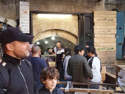 パン屋の前で：「ピタ」という伝統的な円くて平たいパン（アラブ人の必需品）を買いに集まる人々。ここでも小麦が手に入らず、食糧危機を免れない。（ガザ）